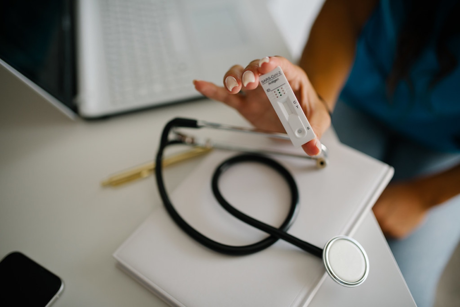 Healthcare professional demonstrates a rapid test while seated at a desk with a stethoscope nearby